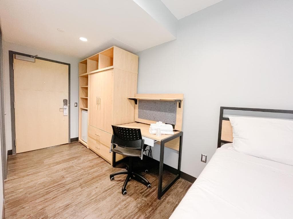 A Queen's University residence room with a bed, desk, chair, and wardrobe